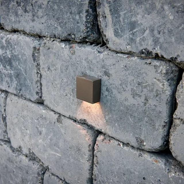 Mur i grov naturstein med en vegglampe